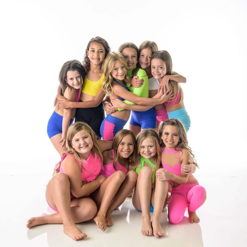 Elementary age dancers posed in front of white background at Prestige Dance Studio